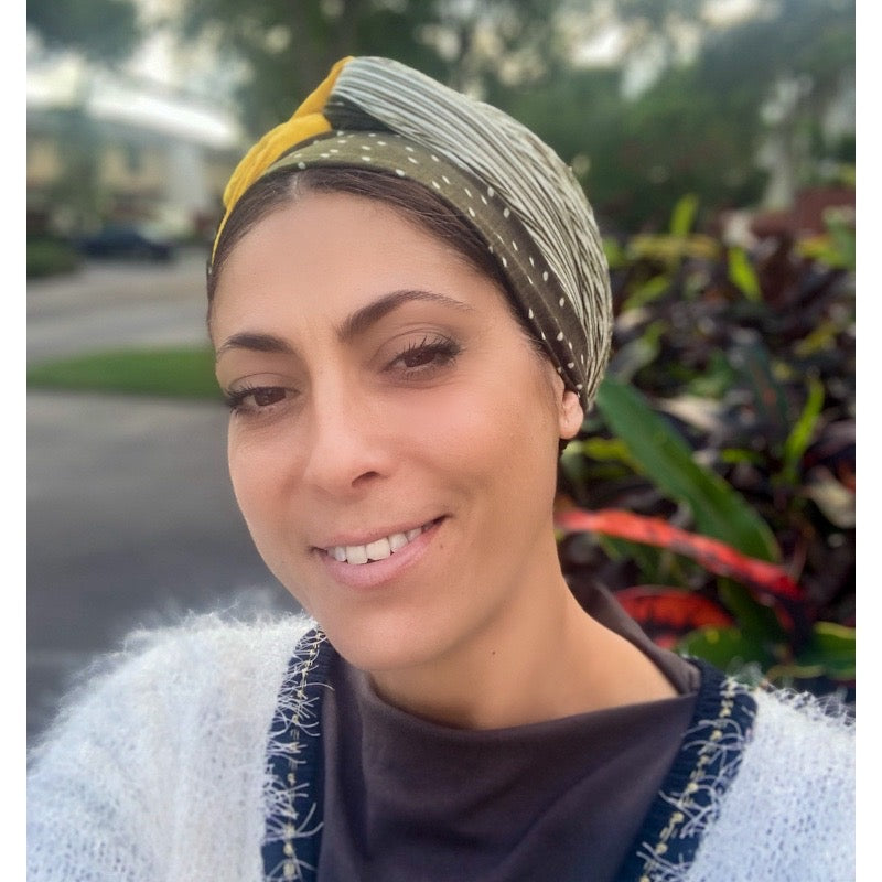 Woman wearing a green and mustard duo tone long scarf headwrap, front view
